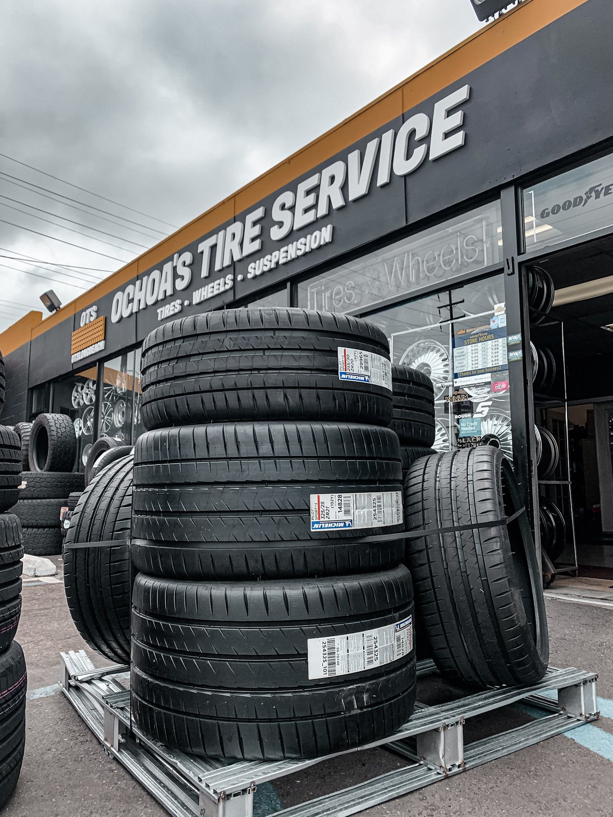Michelin tires stacked outside Ochoa's Tire Service, wheels on display in the window